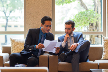 Two Business Men Discussing Document in Lounge