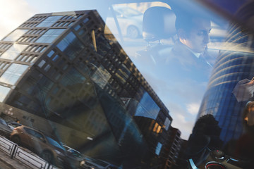 Wide angle shot of city streets reflecting in car window with businessman inside