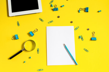 Office supplies on a yellow background. Paper clips and binder