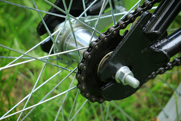 Closeup view of used bicycle single speed rear hub with wide chain and classic steel frame.