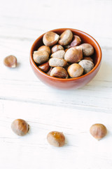 Raw chestnuts in ceramic bowl.
