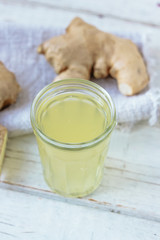 ginger juice in small glass jar with ginger root behind.