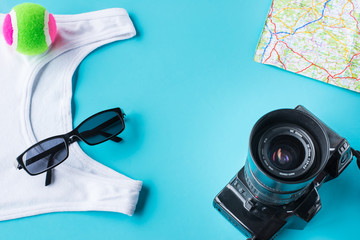 Travel kit: camera, map, t-shirt sun glasses and the small ball. Flat lay composition for social media and travelers. overhead view