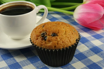 Chocolate muffins with a Cup of coffee and flowers on the table