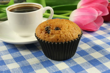 Chocolate muffins with a Cup of coffee and flowers on the table