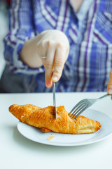 woman hands cutting croissant in a restaurant.