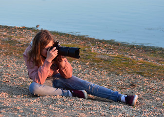 Young girl taking photos on the beach