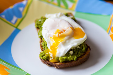 sandwich from the broken eggs on black bread with paste of avocado. shallow depth of field.