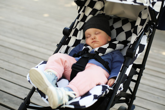 Cute baby in a hat asleep in a baby carriage