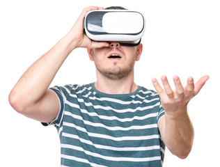 Naklejka premium Amazed man wearing virtual reality goggles watching movies or playing video games gesticulating hands, isolated on white background. Surprised male looking in VR glasses.