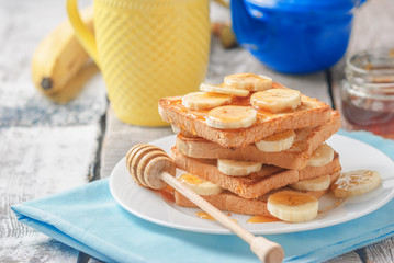 Crispy toast with honey and bananas on white wooden table. Delicious breakfast. close up, selective...