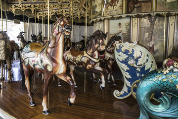 Fototapeta na wymiar Vintage restored carousel hand carved wooden horses on a merry go round ride