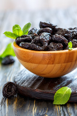 Wooden bowl with dried black plums.