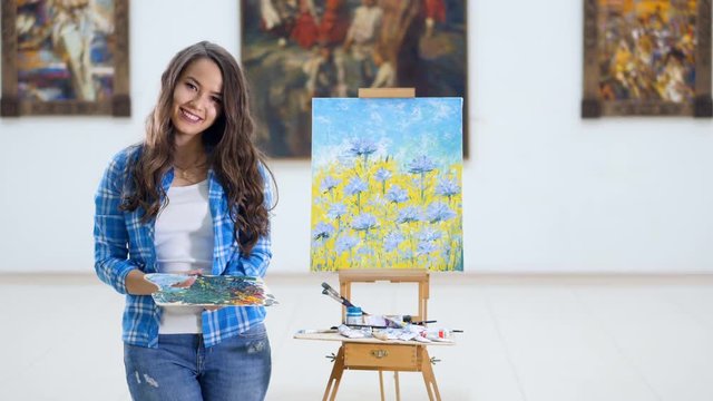 Artist portrait. Girl painter demonstrating her creation. 4K.