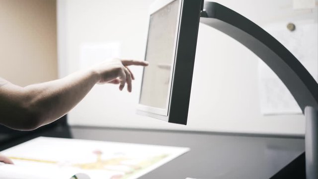 Close up of an unrecognizable printing plant worker choosing settings for a machine to print a poster. Locked down real time medium shot