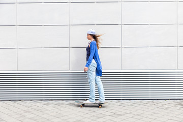 Young girl driving skateboard in urban environment.