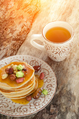 Stack of hot pancakes with nuts, dried fruits and caramel syrup.