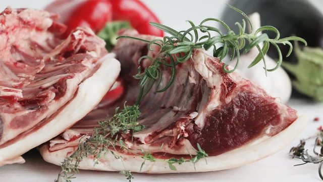 Saddle of mutton - raw red meat - with vegetables. herbs and spices on wooden table. Slow pan.