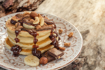 Fototapeta na wymiar Stack of hot pancakes with nuts, bananas and chocolate syrup.