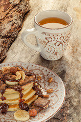 Stack of hot pancakes with nuts, bananas and chocolate syrup.