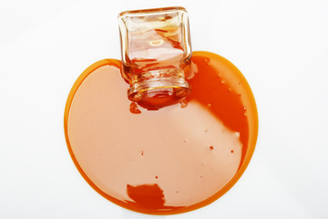 Honey spill from a glass jar on white
