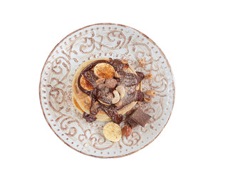 Stack of hot pancakes with nuts, bananas and chocolate syrup. Isolated