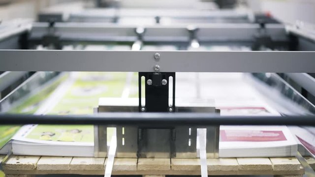 Front view of an industrial printer working making posters. Locked down slow motion close up shot