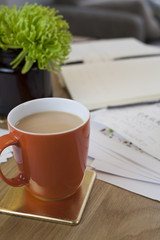 Wood Desk Filled with Papers and Mug of Tea or Coffee and Plant at Home Work
