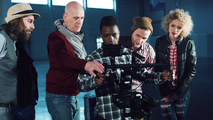 African young man testing handheld camera gyro stabilizin gimbal, the director shows a difference between the mechanical and electronic three-axial video stabilizer © Framestock