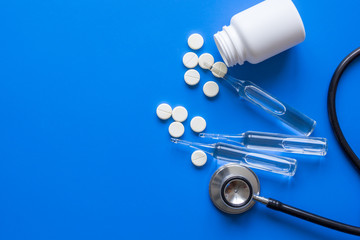 medicine set with stethoscope and vials on doctor's workplace blue background top view mockup