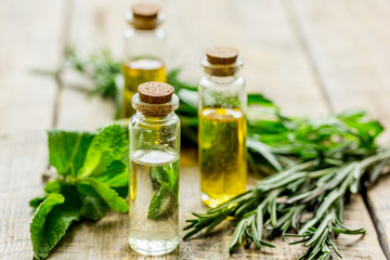 natural cosmetic oil with fresh rosemary and mint on light wooden table background