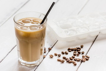 coffee ice cubes and beans with latte on white desk background