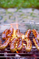 Grilling sausages on barbecue grill. BBQ in the garden. 