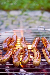 Foto auf Glas Grilling sausages on barbecue grill. BBQ in the garden.  © encierro