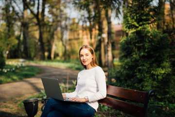 Young pretty businesswoman is sitting on the bench in city.