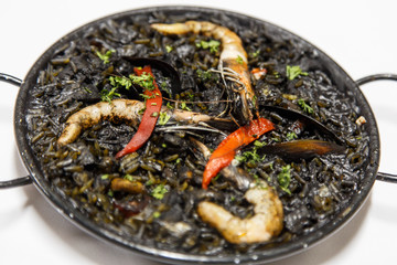 Black risotto with seafood on white plate, arroz negro from spain