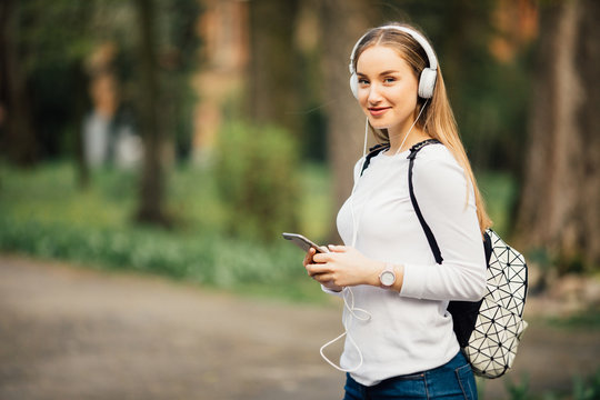 Portrait of young attractive girl in urban background listening to music with headphones