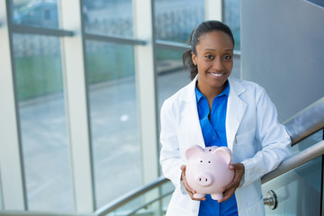 Closeup portrait, healthcare professional holding piggy bank isolated indoors clinic hospital background.  Health savings financial concept