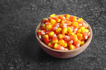 Bowl with tasty Halloween candies on dark background