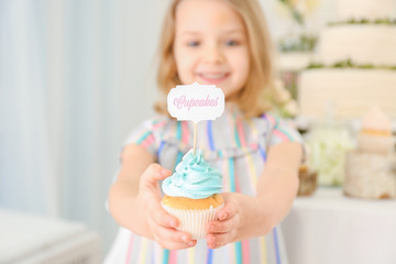 Obraz na płótnie Canvas Cute little girl with tasty cupcake, closeup