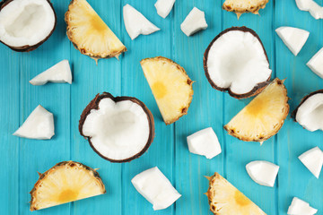 Composition of fresh coconut and pineapple slices on color wooden background
