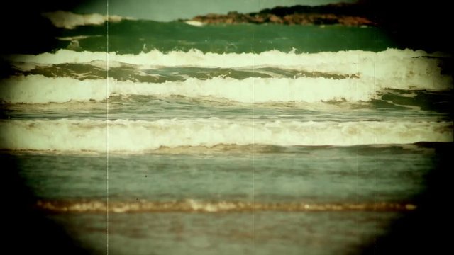 Retro style 1660s film of waves on a sandy beach
