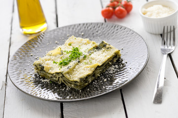 fresh Italian pasta spinach lasagne dish traditional vegetarian vegan cheese parsley plate layers olive oil tomatoes white wooden rustic plate