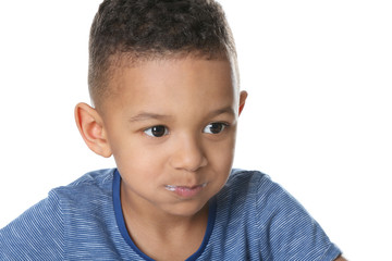 Cute African American boy eating yogurt on white background, closeup