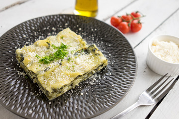 fresh Italian pasta spinach lasagne dish traditional vegetarian vegan cheese parsley plate layers olive oil tomatoes white wooden rustic plate