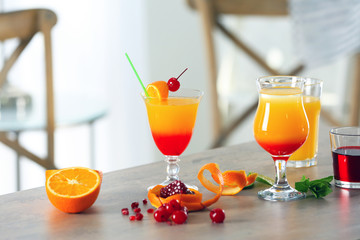 Glasses of Tequila Sunrise cocktail with ingredients on table
