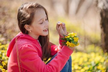 the happy girl collects flowers in the spring wood