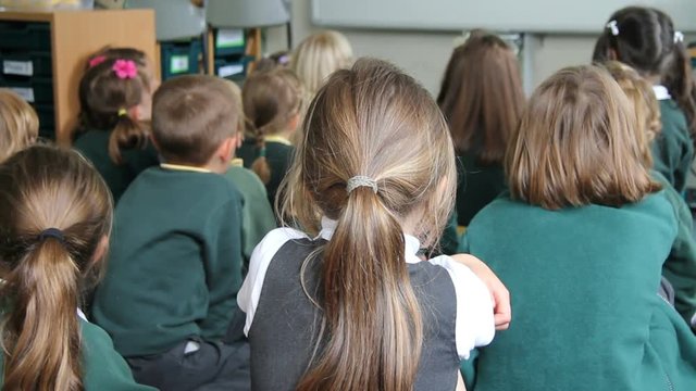 Engaged school children listening to the class teacher