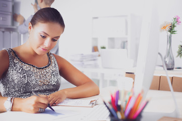 Fashion designers working in studio sitting on the desk