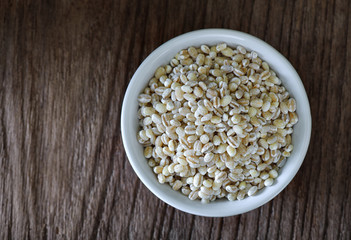 pearl barley in white bowl on wood